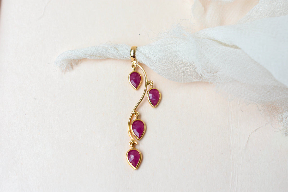 18K gold pendant with four bezel-set pear rubies on a vine design