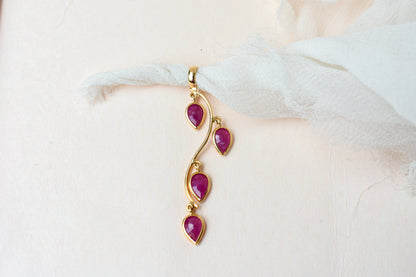 18K gold pendant with four bezel-set pear rubies on a vine design