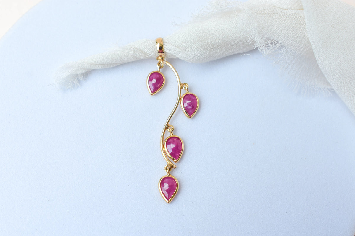18K gold pendant with four bezel-set pear rubies on a vine design