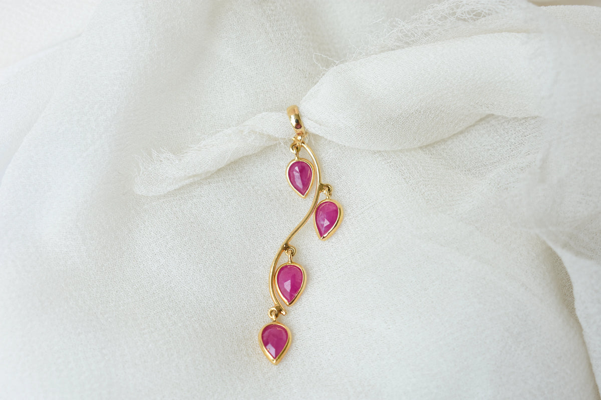 18K gold pendant with four bezel-set pear rubies on a vine design