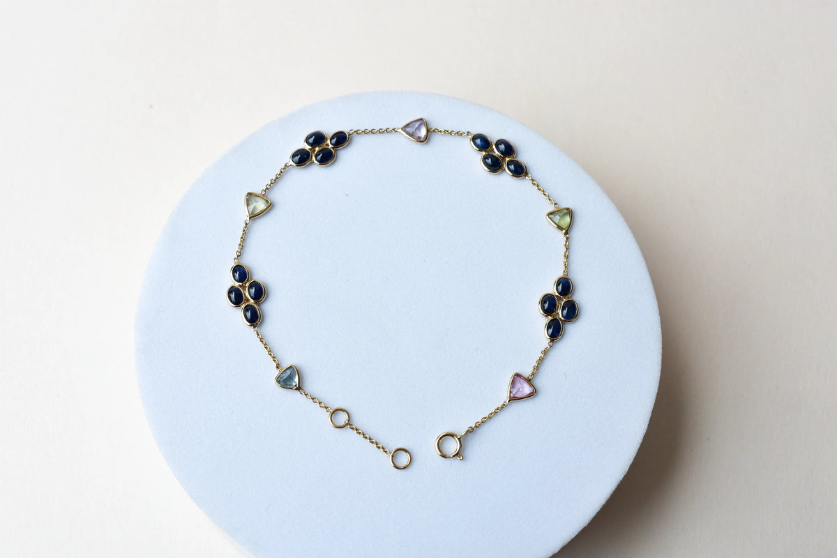 18K gold bracelet with blue sapphire clusters and multi-color trillion sapphire accents
