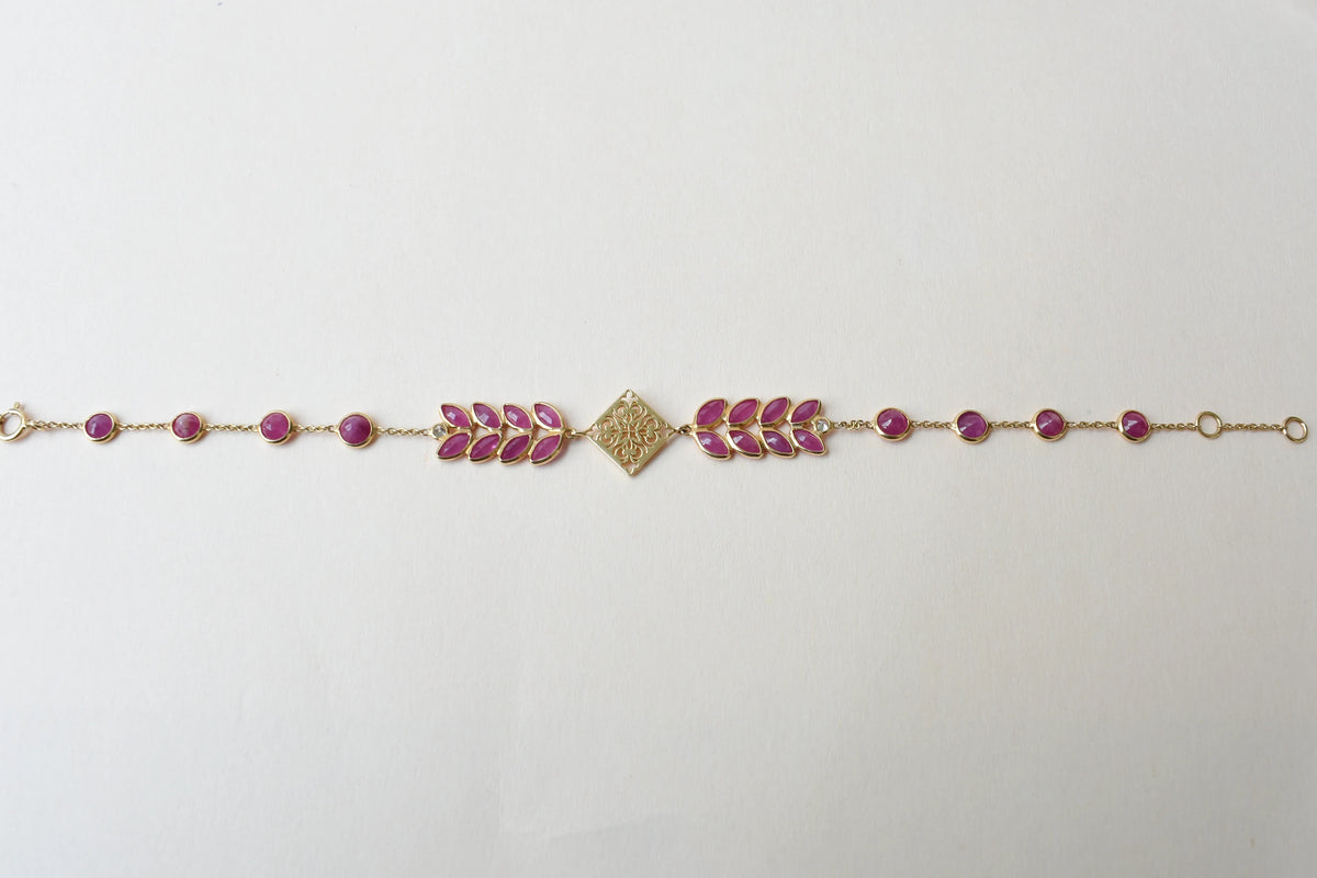 18K gold bracelet with round ruby stations and a diamond accent