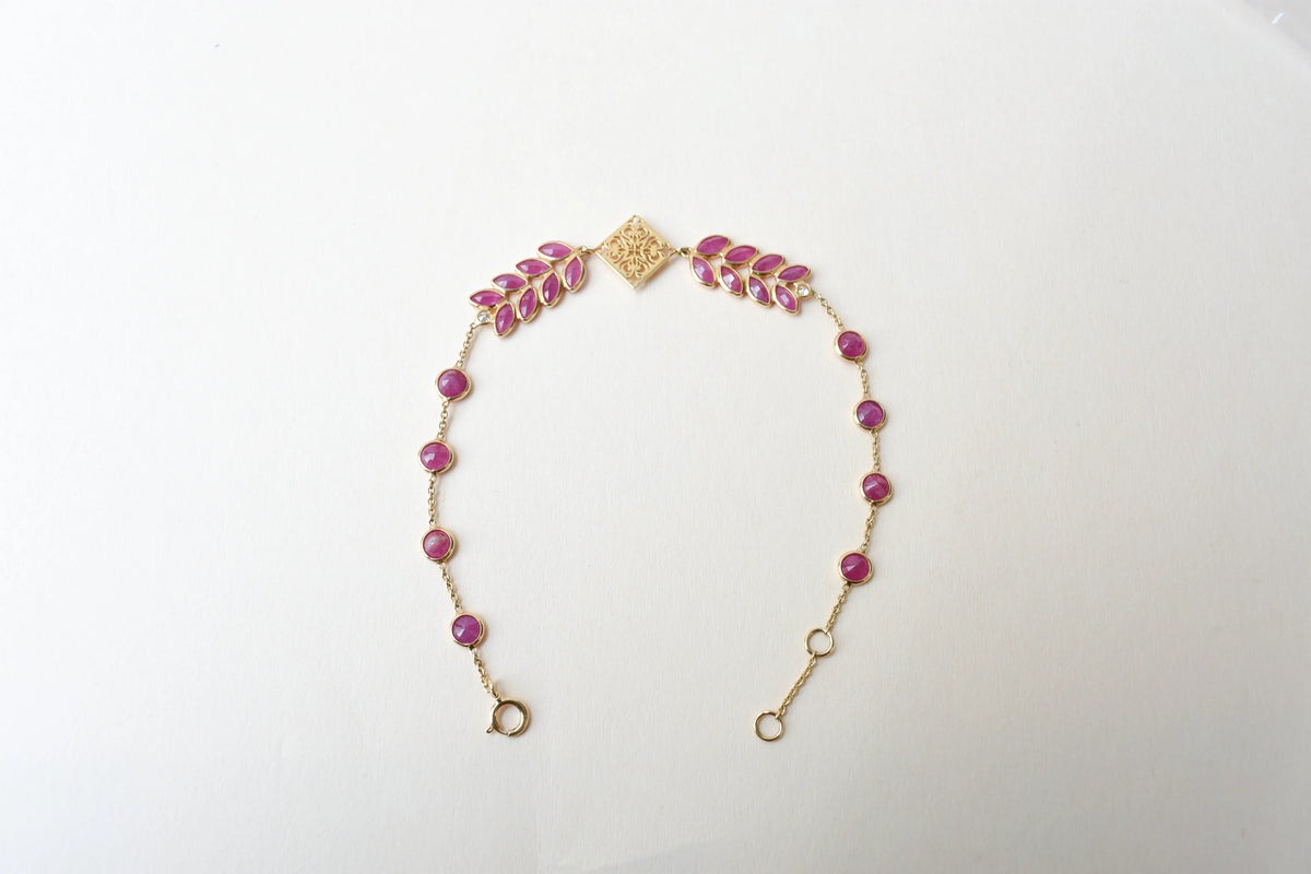 18K gold bracelet with round ruby stations and a diamond accent