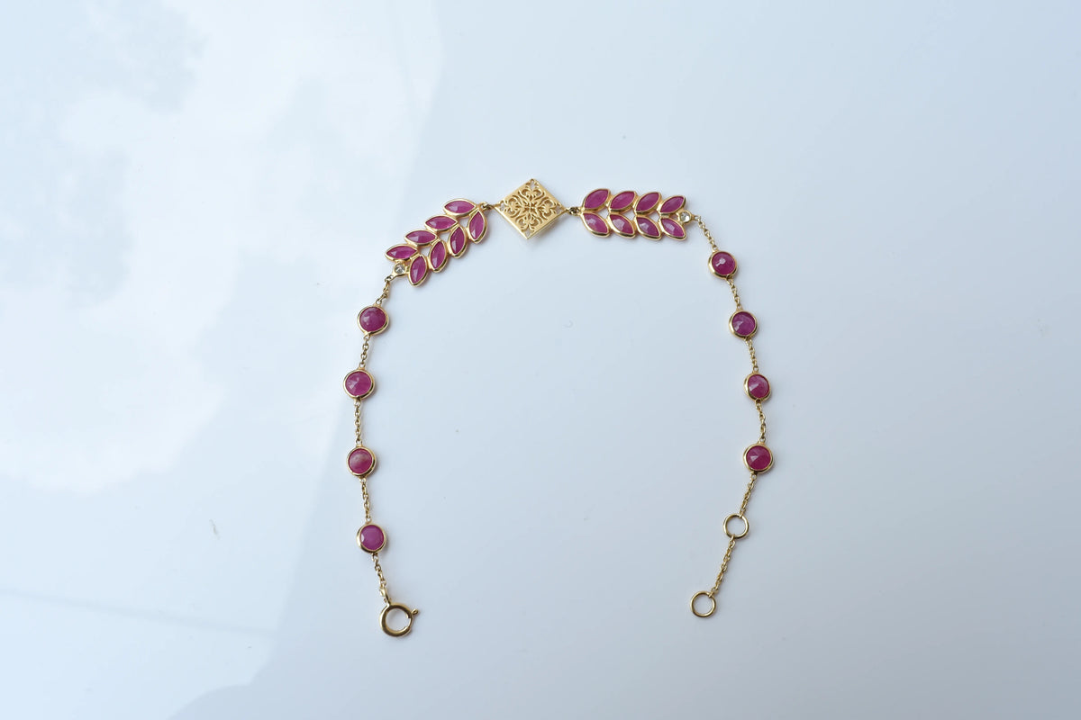 18K gold bracelet with round ruby stations and a diamond accent