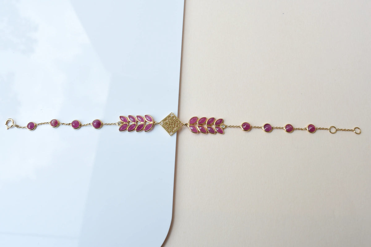18K gold bracelet with round ruby stations and a diamond accent