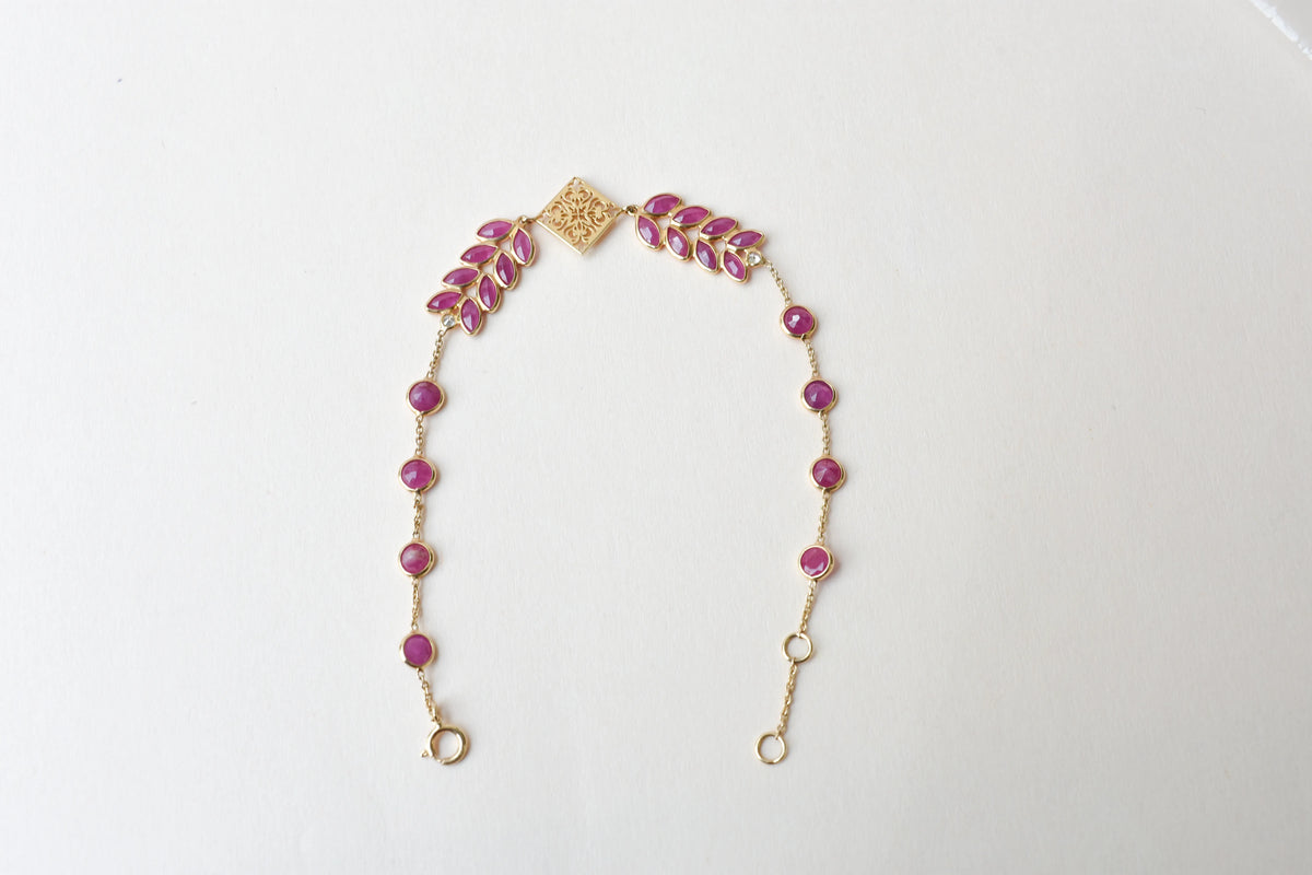 18K gold bracelet with round ruby stations and a diamond accent