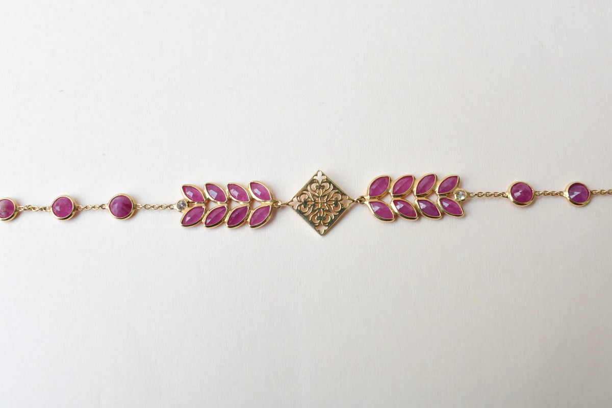18K gold bracelet with round ruby stations and a diamond accent