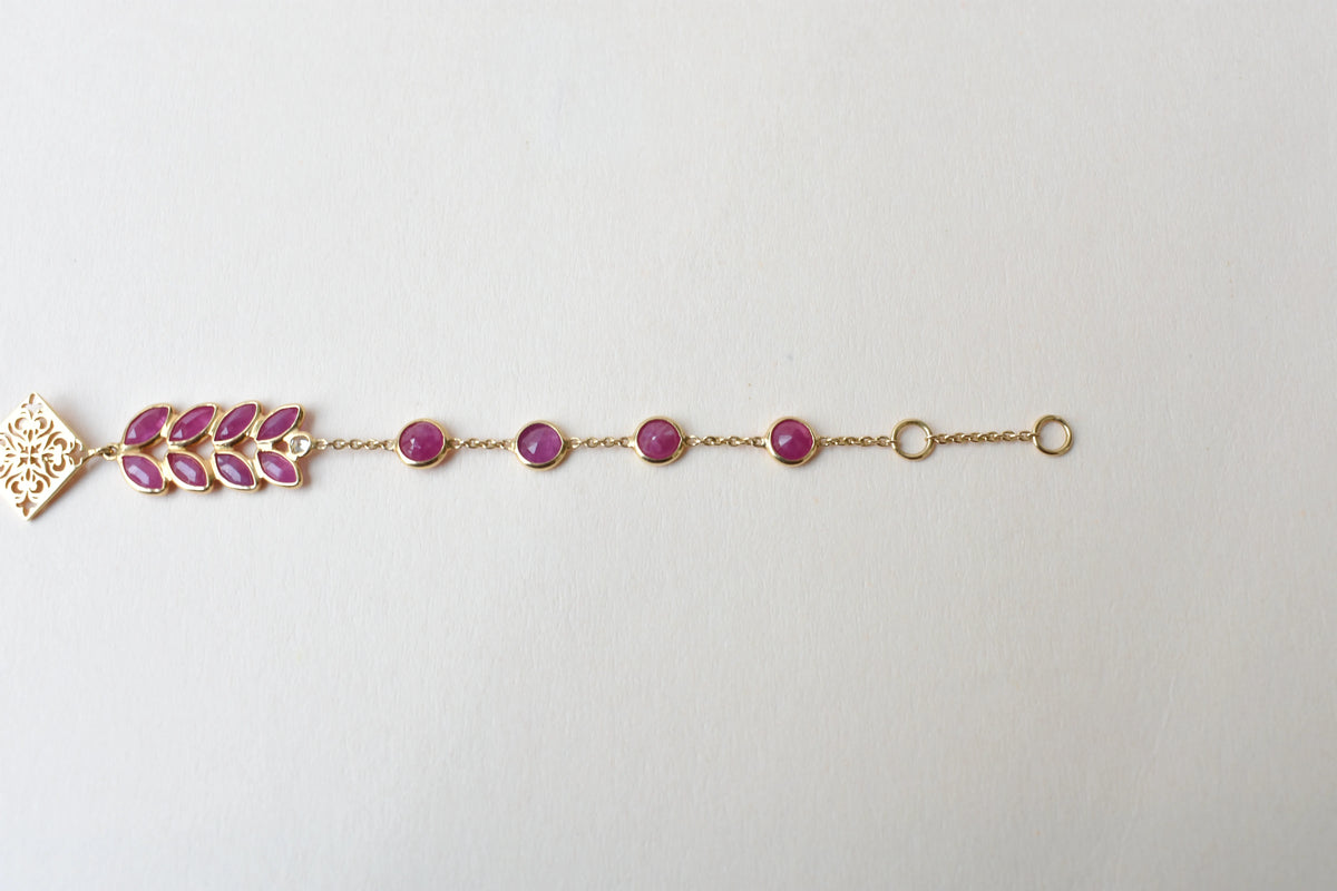 18K gold bracelet with round ruby stations and a diamond accent