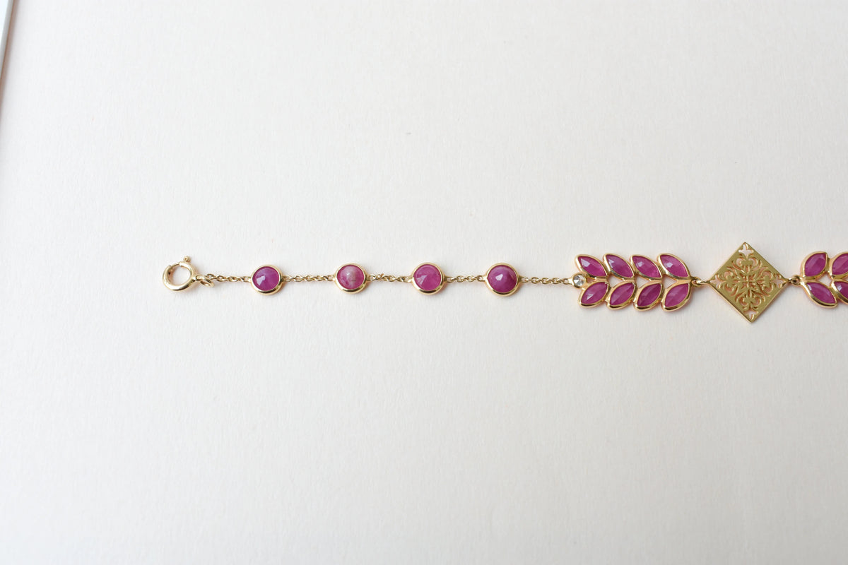18K gold bracelet with round ruby stations and a diamond accent