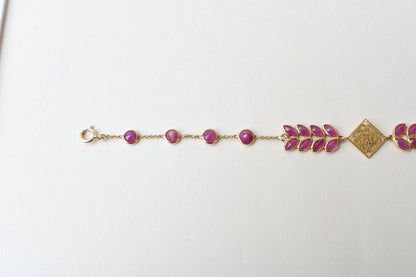 18K gold bracelet with round ruby stations and a diamond accent