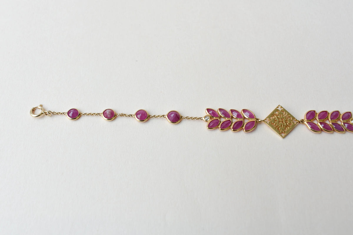 18K gold bracelet with round ruby stations and a diamond accent