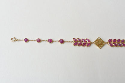 18K gold bracelet with round ruby stations and a diamond accent