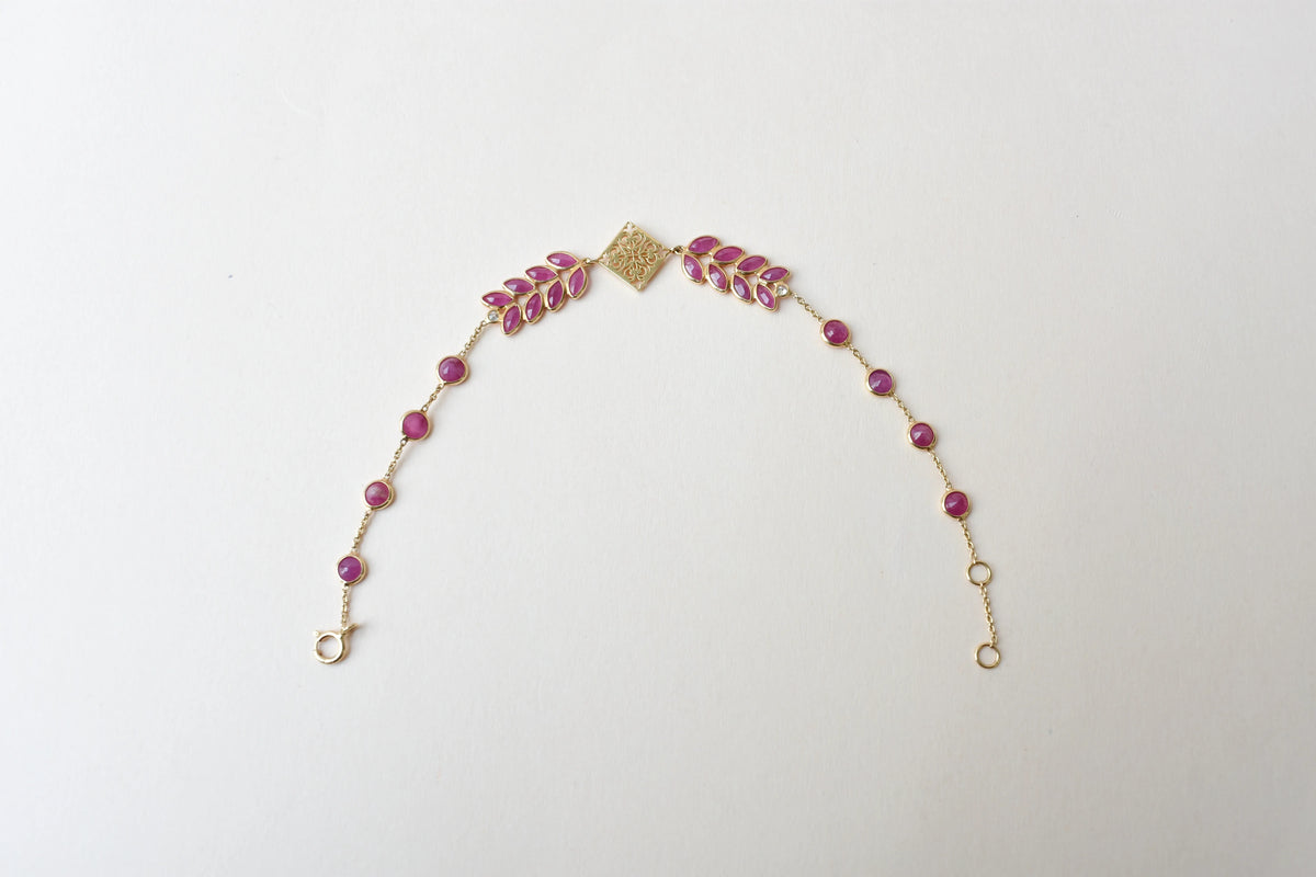 18K gold bracelet with round ruby stations and a diamond accent