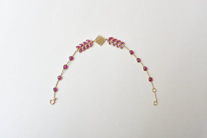 18K gold bracelet with round ruby stations and a diamond accent