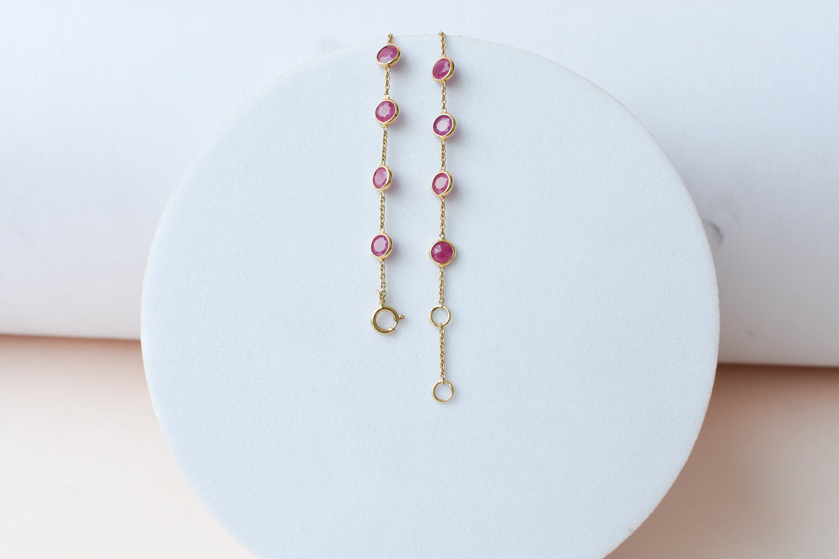18K gold bracelet with round ruby stations and a diamond accent