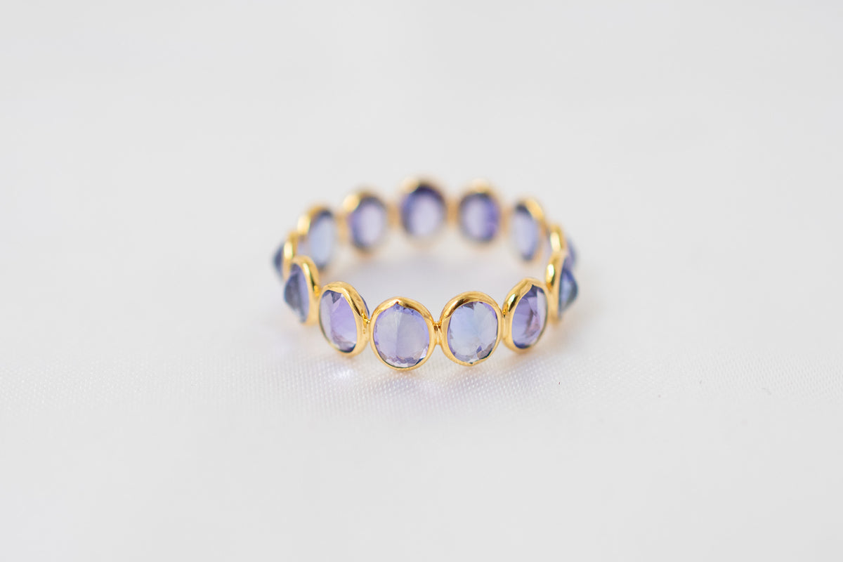 Oval-cut tanzanite gemstone eternity ring in 18K gold with bezel setting