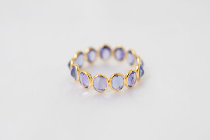 Oval-cut tanzanite gemstone eternity ring in 18K gold with bezel setting