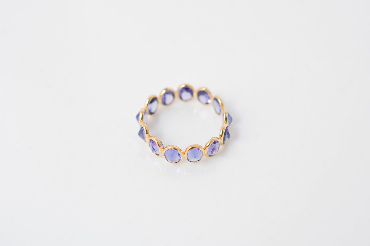Oval-cut tanzanite gemstone eternity ring in 18K gold with bezel setting