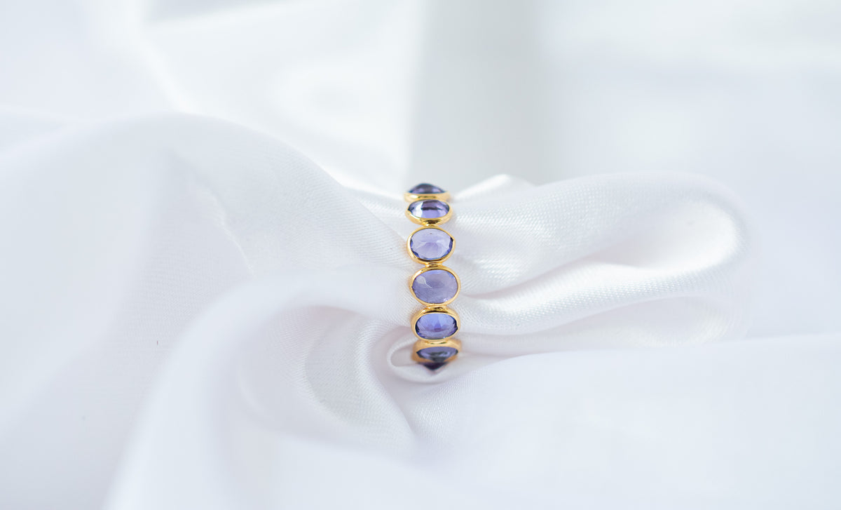 Oval-cut tanzanite gemstone eternity ring in 18K gold with bezel setting