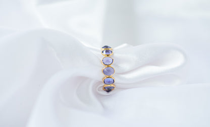 Oval-cut tanzanite gemstone eternity ring in 18K gold with bezel setting
