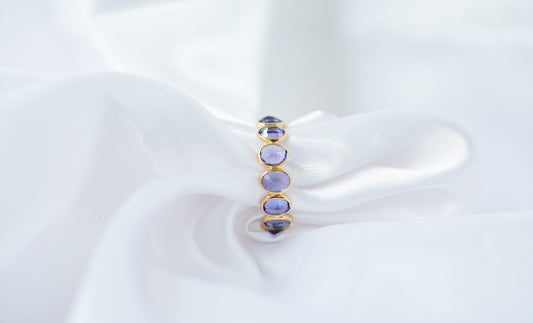 Oval-cut tanzanite gemstone eternity ring in 18K gold with bezel setting