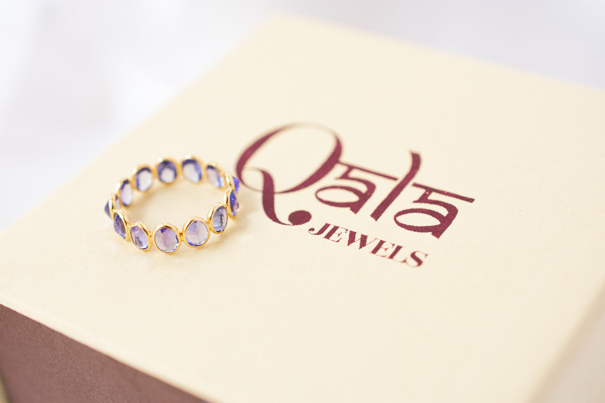 Oval-cut tanzanite gemstone eternity ring in 18K gold with bezel setting