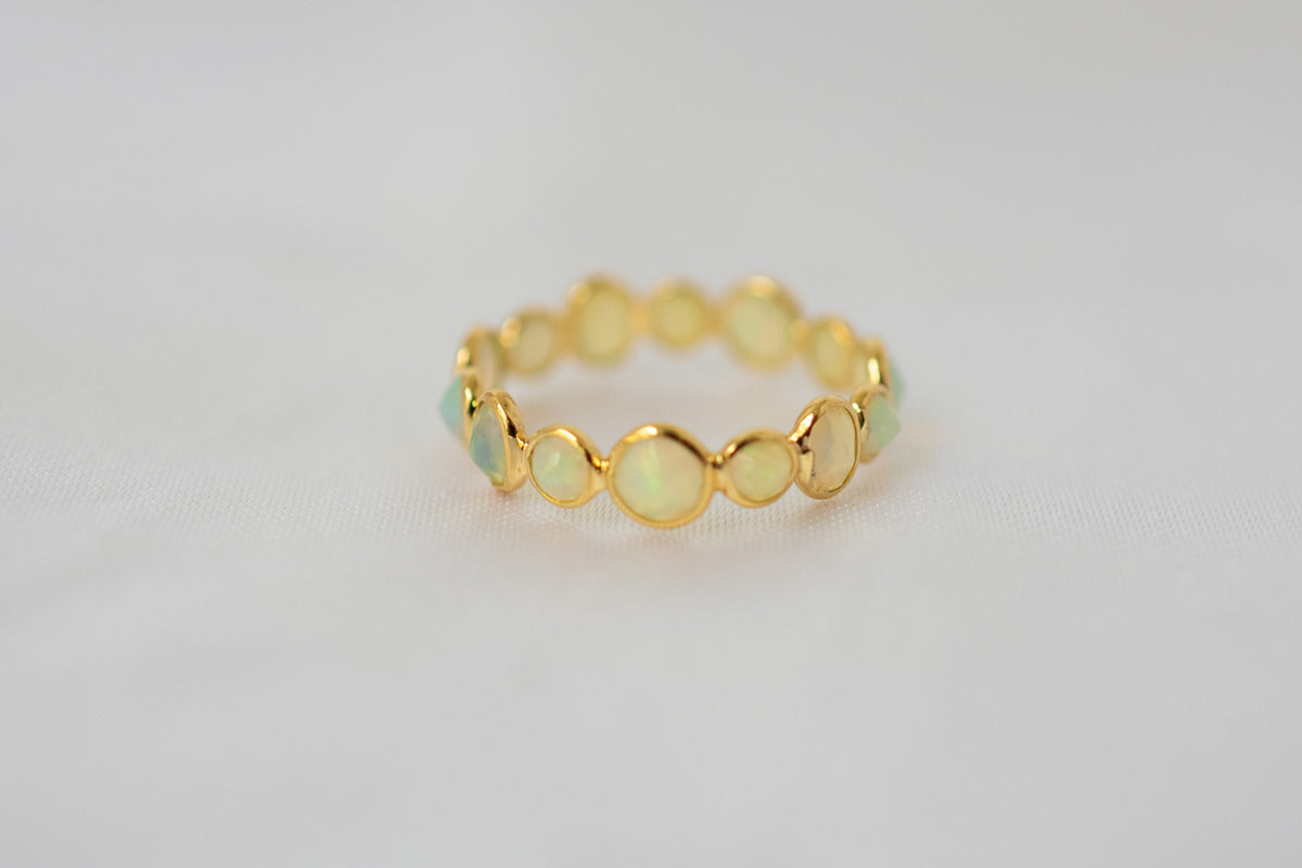 Cabochon opal gemstone eternity ring in 18K gold with bezel setting