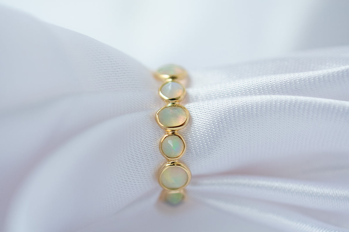 Cabochon opal gemstone eternity ring in 18K gold with bezel setting