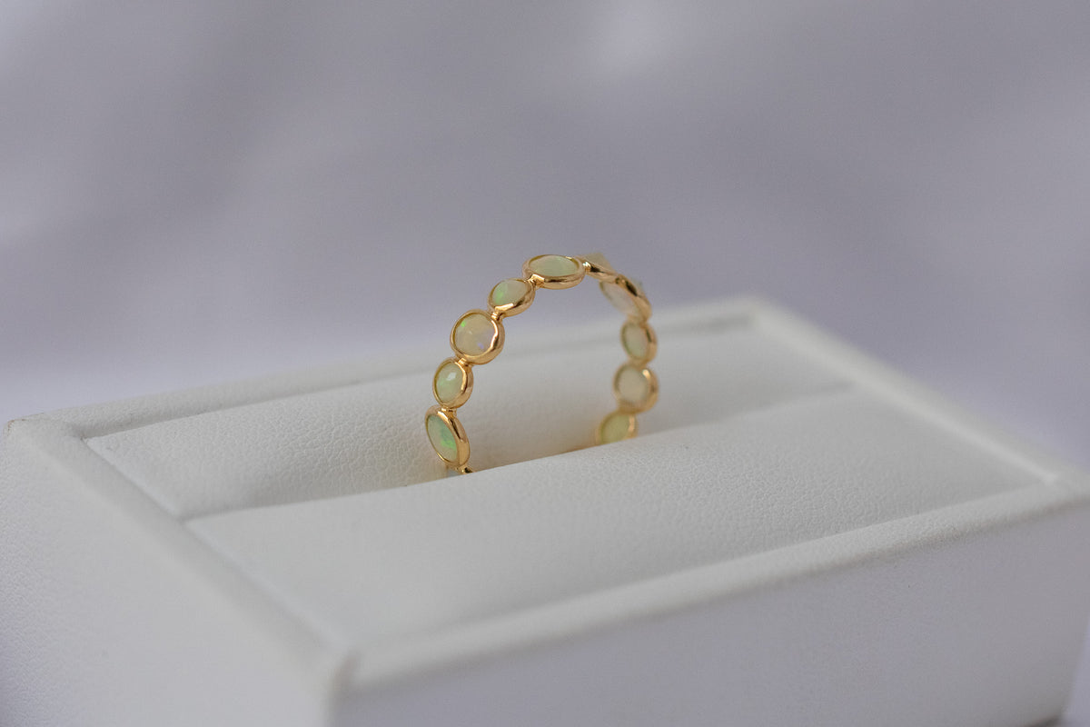 Cabochon opal gemstone eternity ring in 18K gold with bezel setting