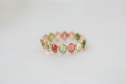 Oval-cut multicolor tourmaline gemstone eternity ring in 18K gold with bezel setting