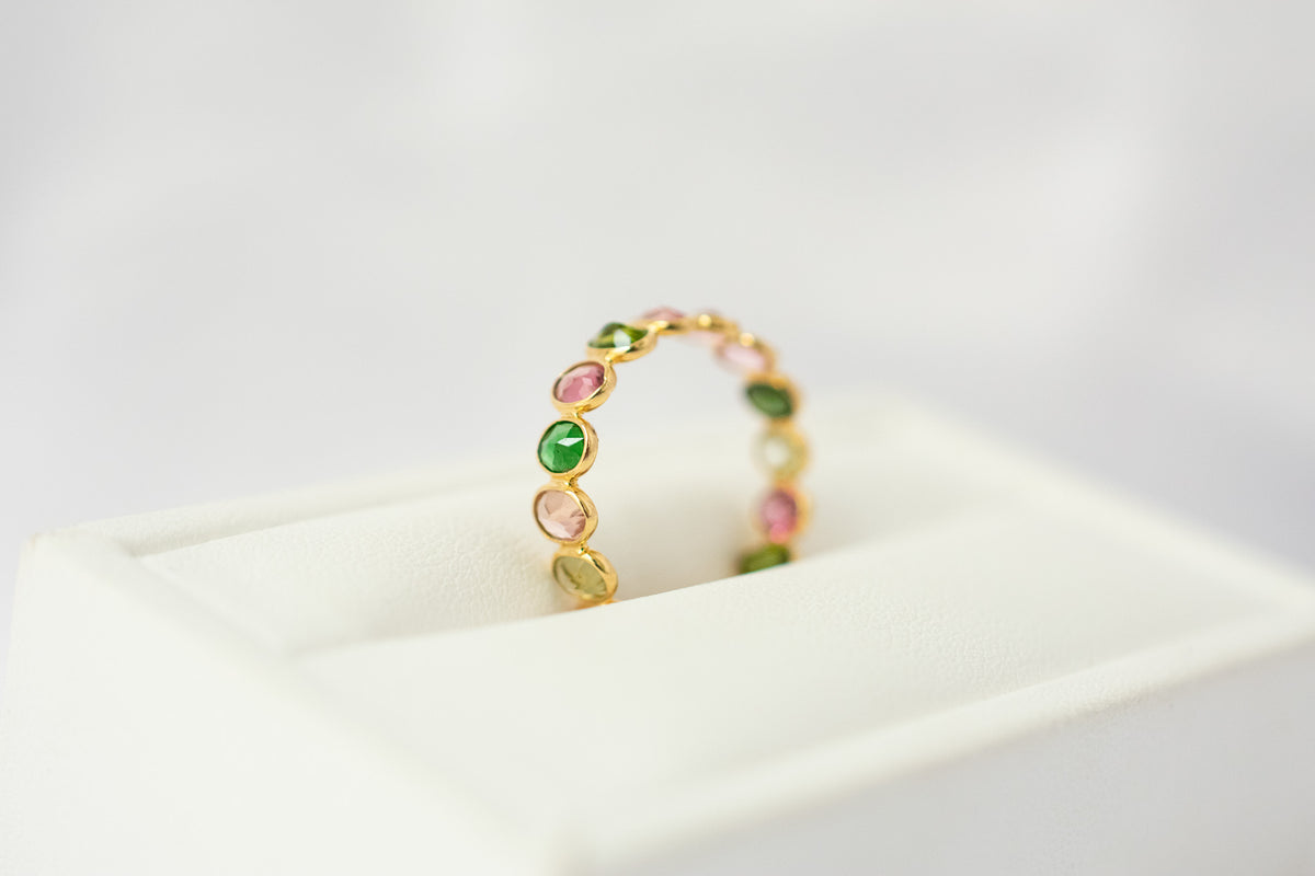 Oval-cut multicolor tourmaline gemstone eternity ring in 18K gold with bezel setting