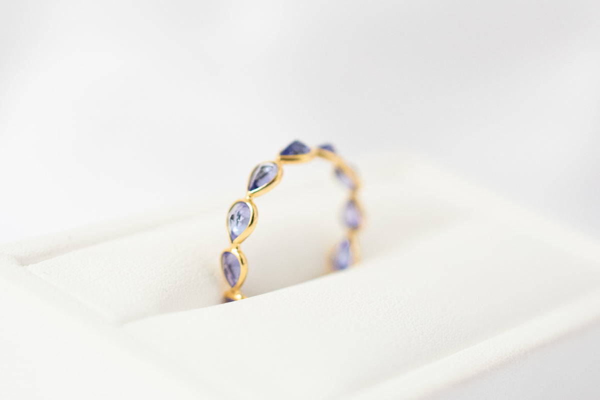 Pear-cut tanzanite gemstone eternity ring in 18K gold with bezel setting
