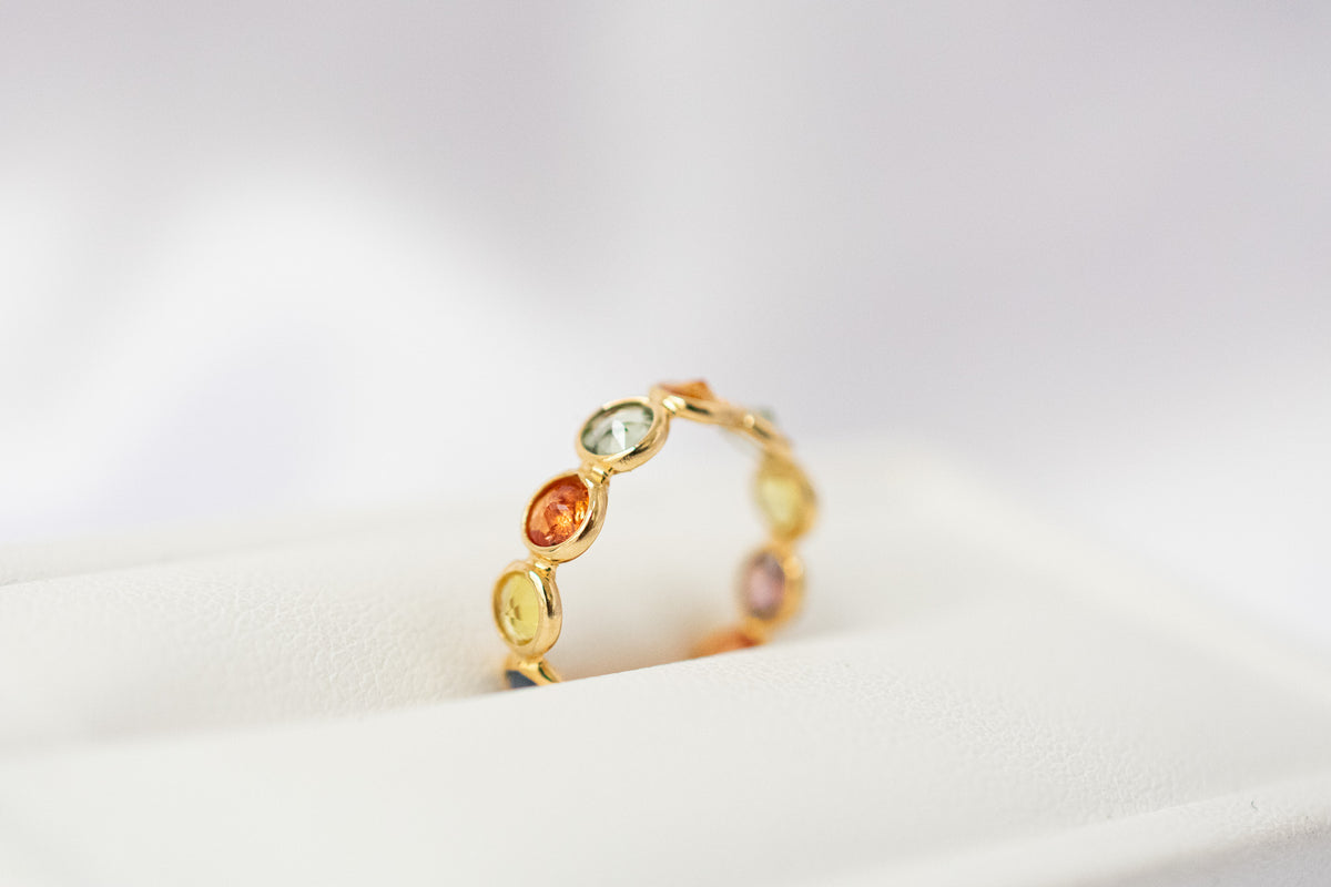 Round-cut multicolor sapphire eternity ring in 18K gold with bezel setting