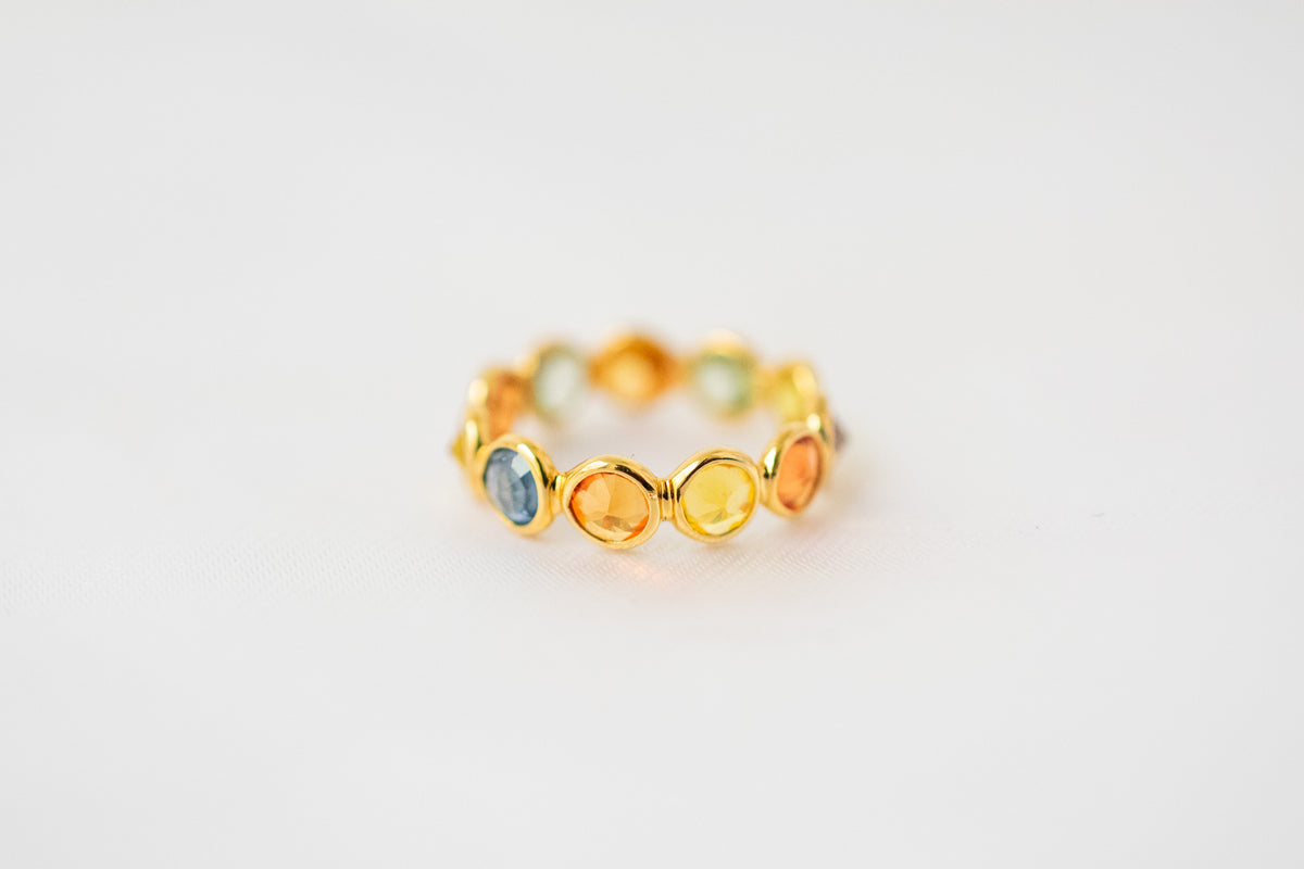 Round-cut multicolor sapphire eternity ring in 18K gold with bezel setting