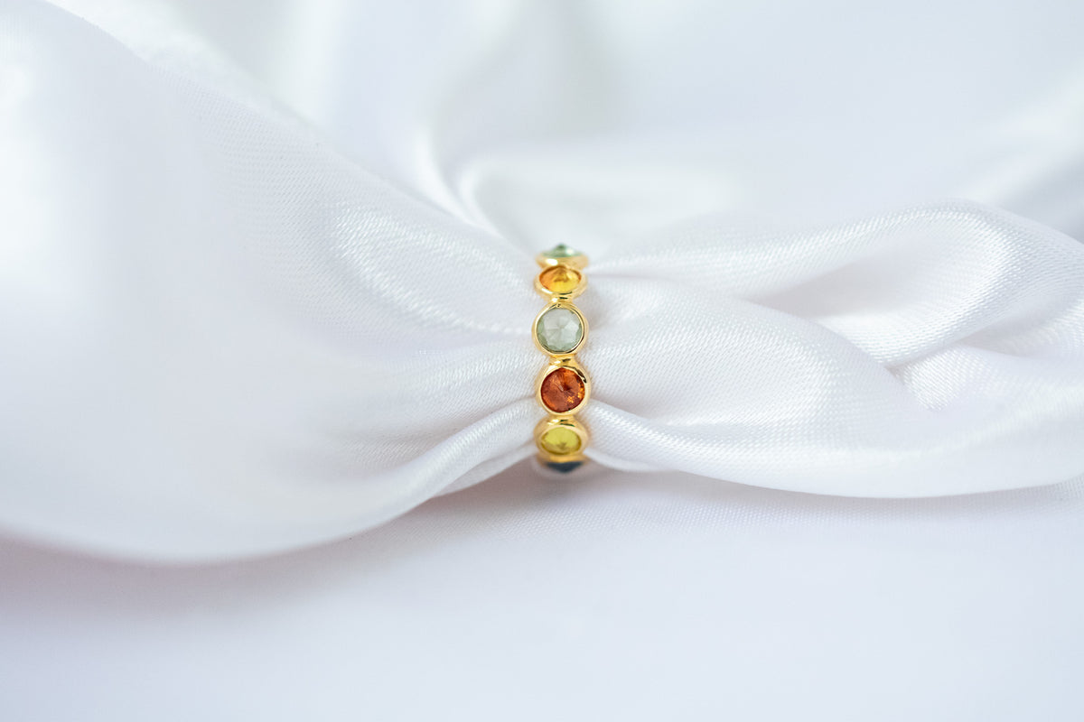Round-cut multicolor sapphire eternity ring in 18K gold with bezel setting