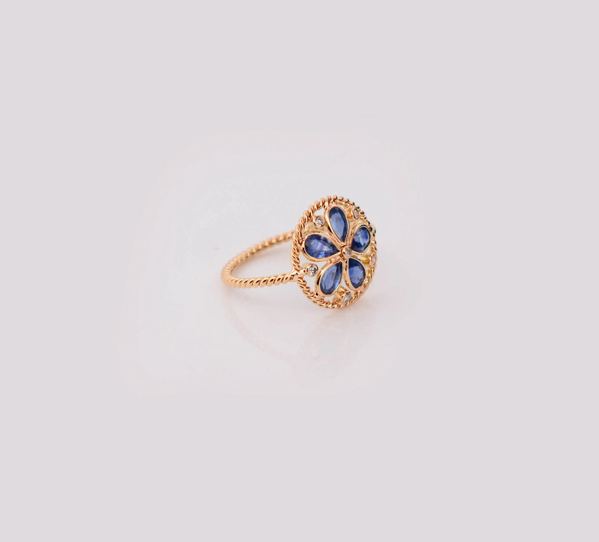 18K gold flower cluster ring with blue sapphire petals and a center diamond