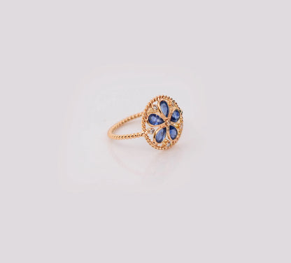 18K gold flower cluster ring with blue sapphire petals and a center diamond