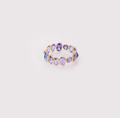 18K gold eternity ring with mixed-cut tanzanite stones in a mosaic pattern