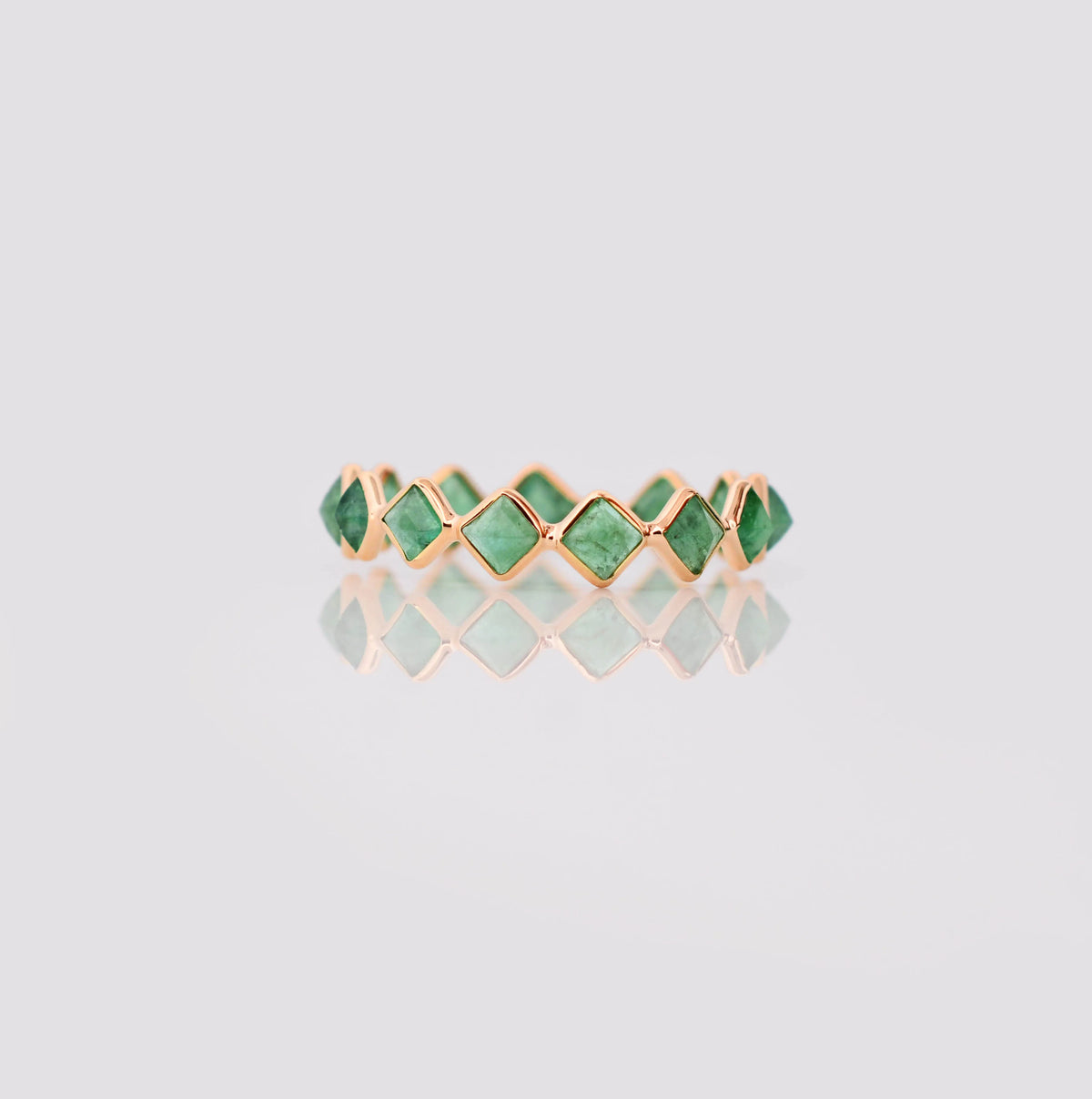 18K gold eternity ring with square and kite-cut emeralds in a zigzag pattern