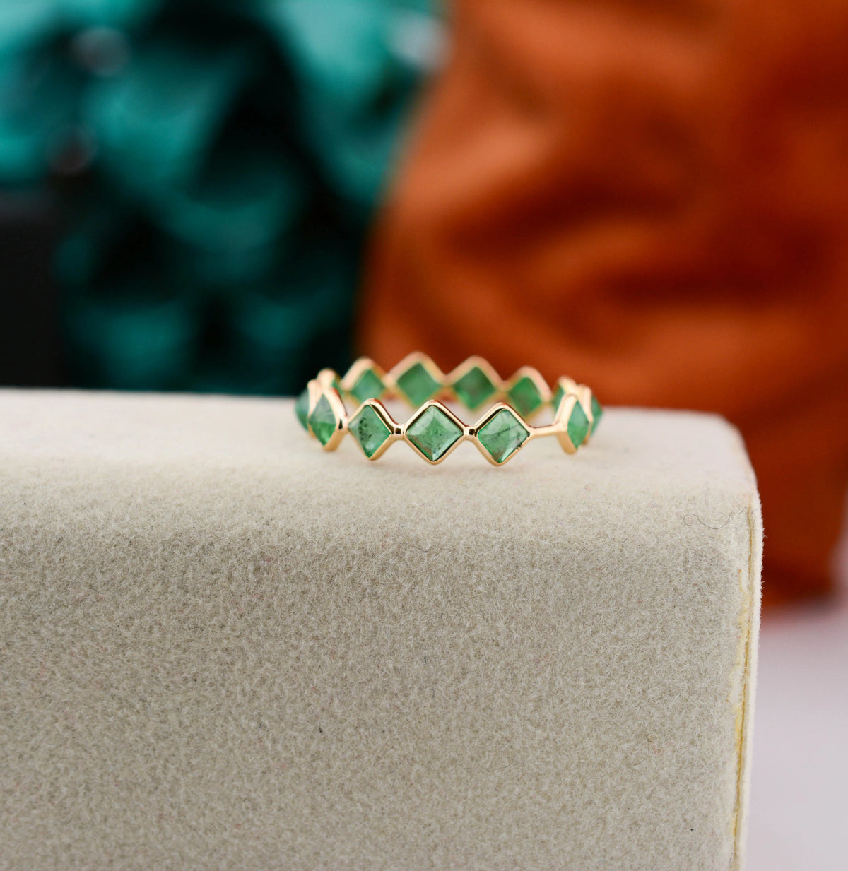 18K gold eternity ring with square and kite-cut emeralds in a zigzag pattern