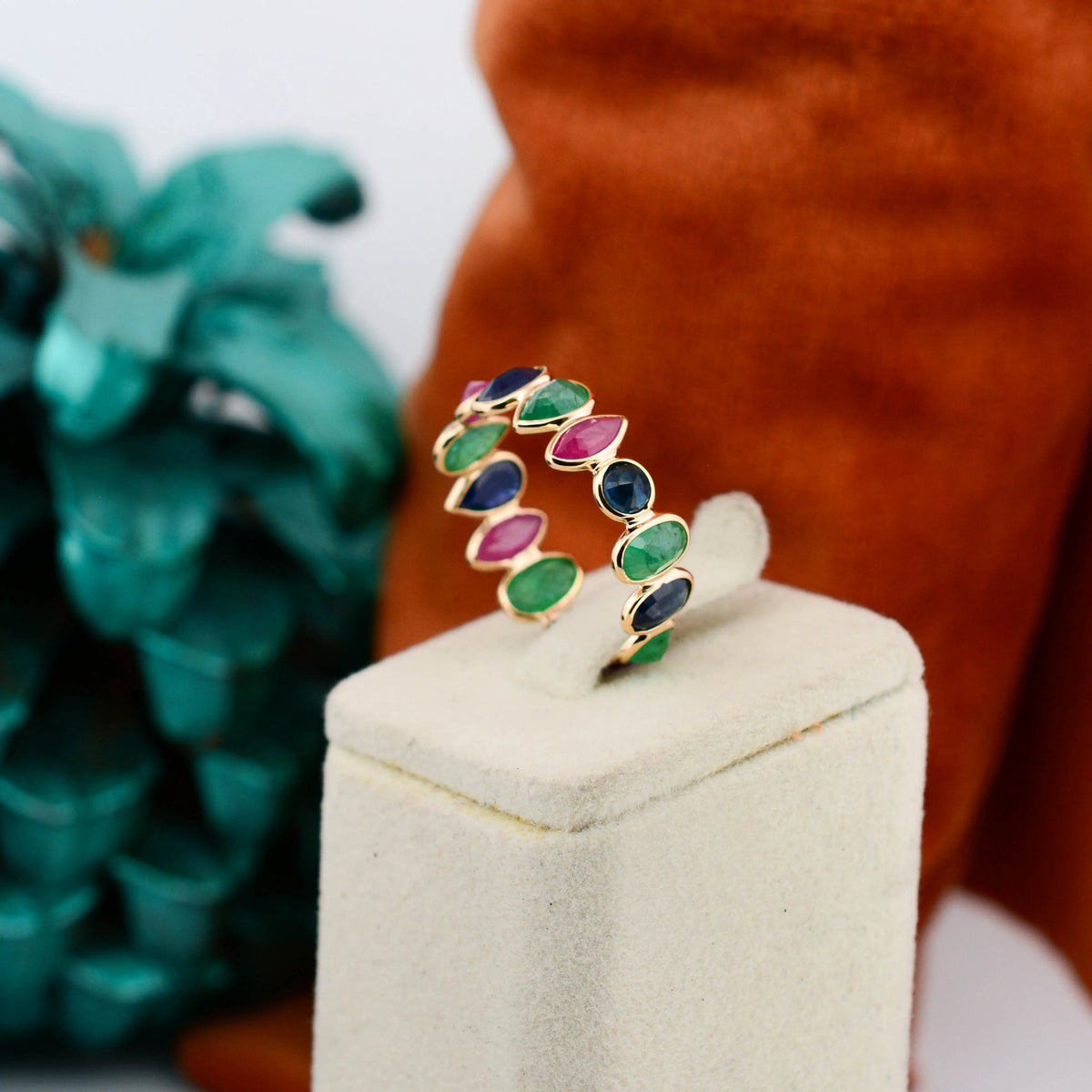 18K gold eternity ring with mixed sapphire, emerald, and ruby gemstones