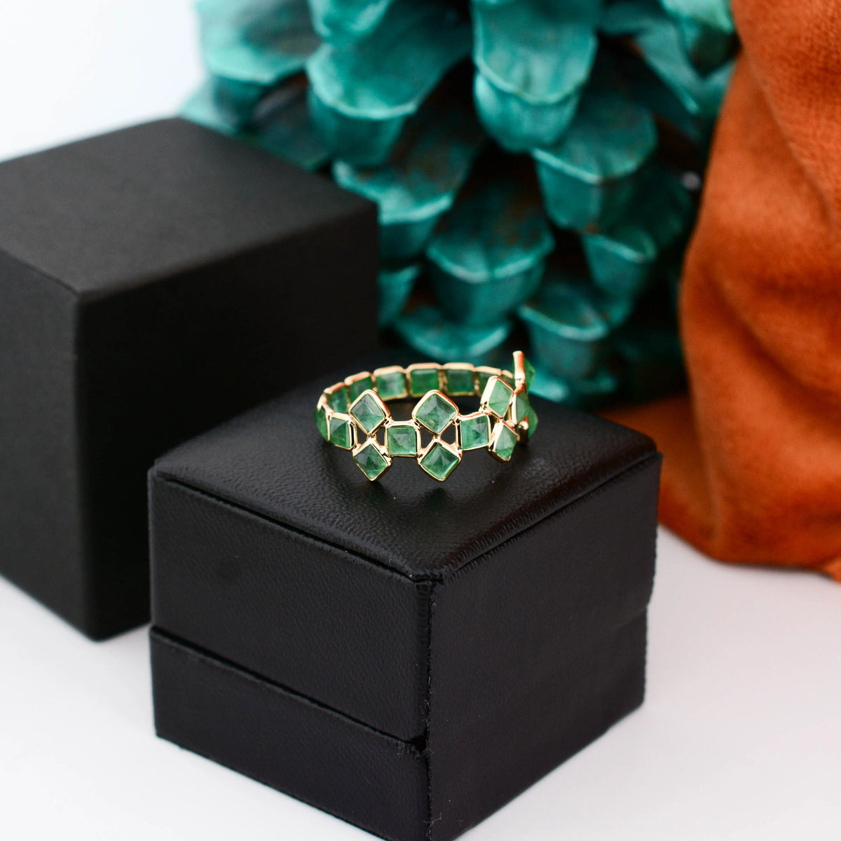 18K gold eternity ring with square-cut emeralds in a checkerboard lattice pattern