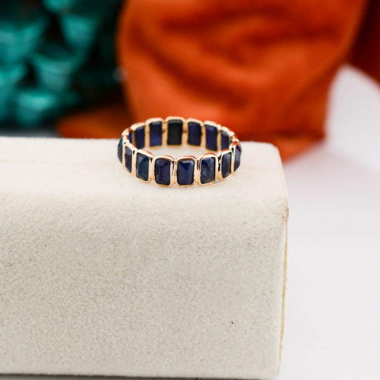 18K gold eternity ring with bezel-set emerald-cut blue sapphires